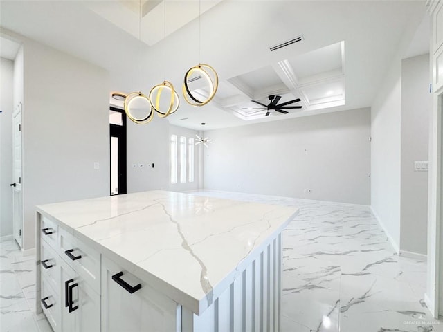 kitchen featuring light stone counters, coffered ceiling, a center island, and white cabinets