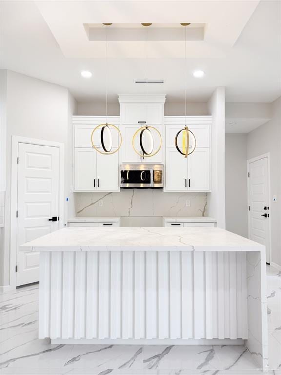 bar with light stone countertops, a raised ceiling, hanging light fixtures, and white cabinets