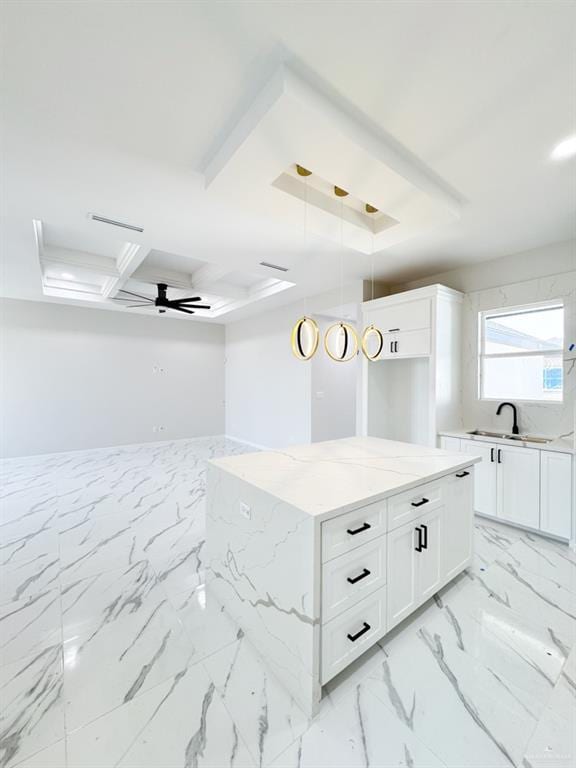 kitchen featuring pendant lighting, white cabinetry, sink, ceiling fan, and light stone countertops