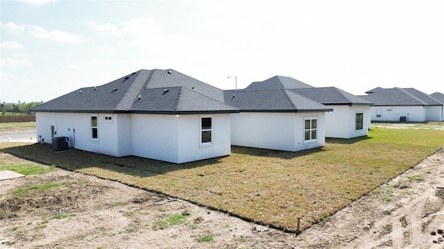 back of house with cooling unit and a lawn