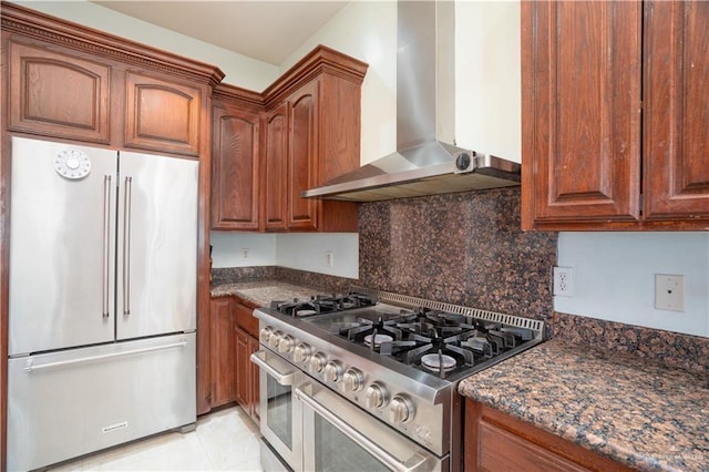 kitchen featuring tasteful backsplash, brown cabinets, wall chimney exhaust hood, and premium appliances