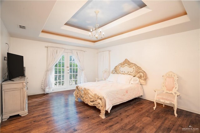 bedroom featuring a chandelier, visible vents, wood finished floors, and a raised ceiling