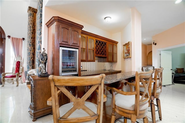 bar with indoor wet bar, arched walkways, and beverage cooler