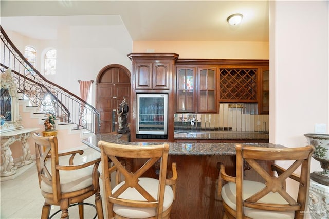 bar featuring decorative backsplash, stairway, and indoor wet bar