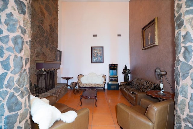 living area with visible vents, tile patterned floors, a high ceiling, and a fireplace