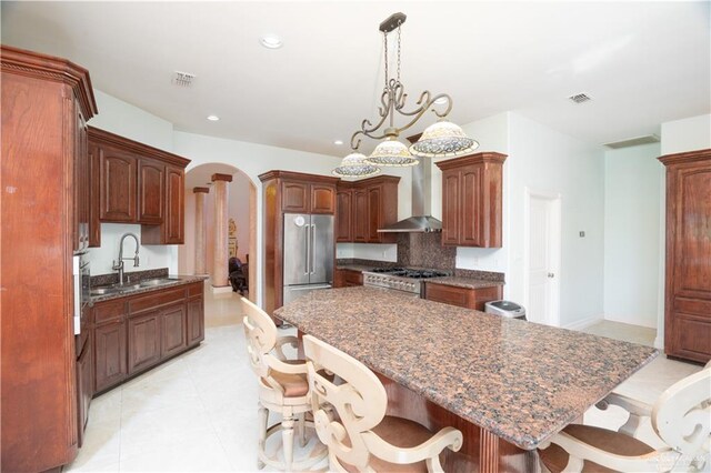 kitchen with visible vents, wall chimney exhaust hood, a sink, high quality fridge, and range
