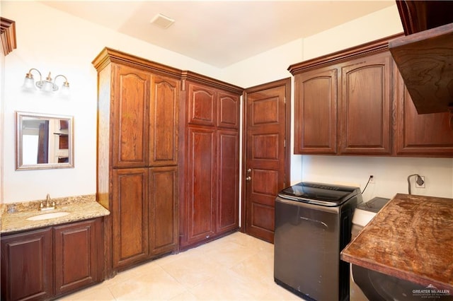 laundry room featuring light tile patterned flooring, a sink, and cabinet space