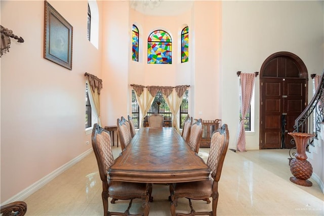 tiled dining room with a high ceiling and baseboards