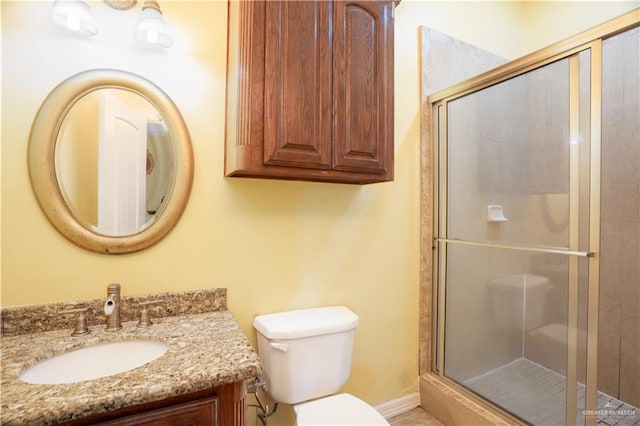 bathroom with a shower stall, vanity, baseboards, and toilet