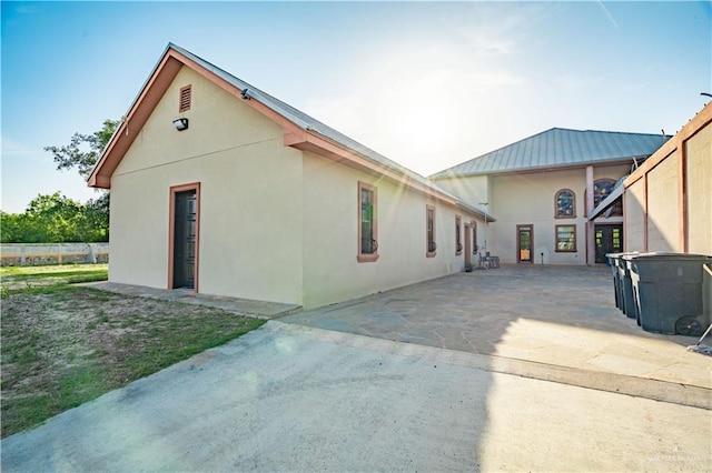 back of property with a standing seam roof, metal roof, and stucco siding