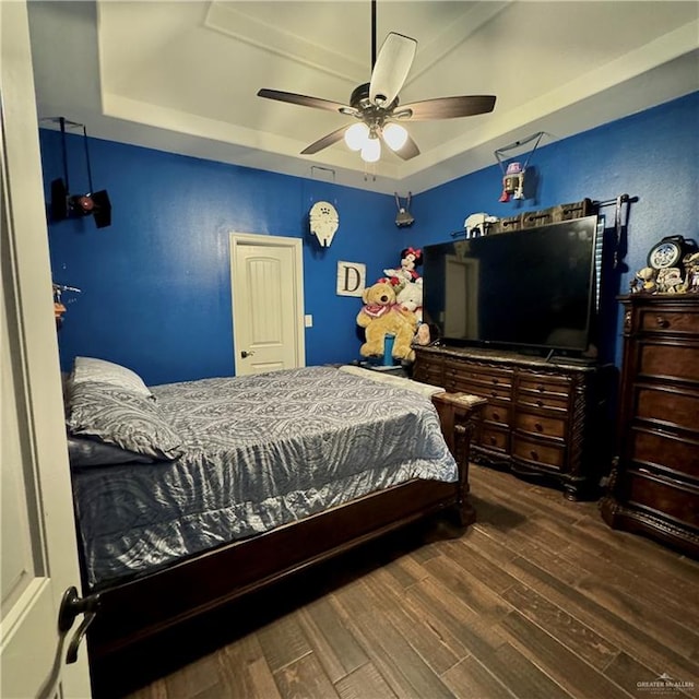 bedroom with hardwood / wood-style floors, a raised ceiling, and ceiling fan