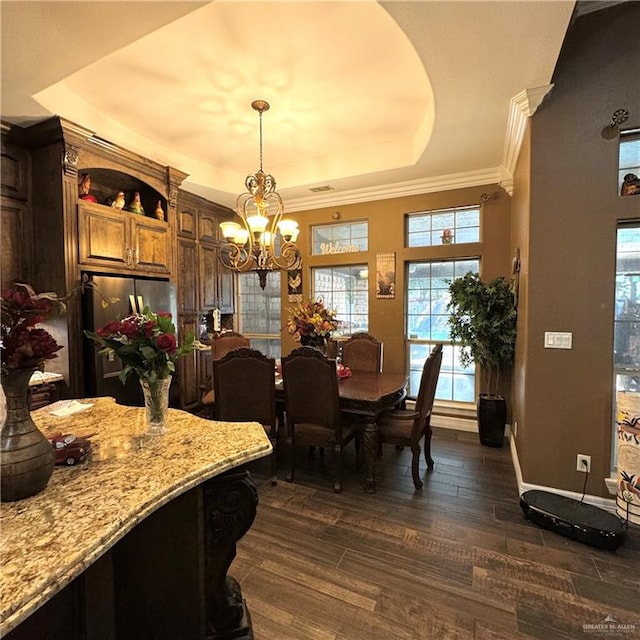 dining space featuring a raised ceiling, dark hardwood / wood-style flooring, ornamental molding, and an inviting chandelier