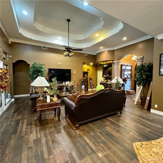 living room with dark hardwood / wood-style floors, a raised ceiling, ornamental molding, and decorative columns