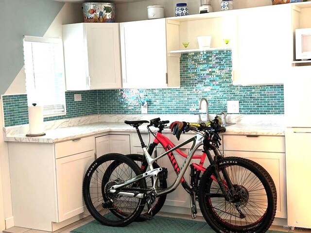 kitchen featuring light stone counters, decorative backsplash, and white appliances