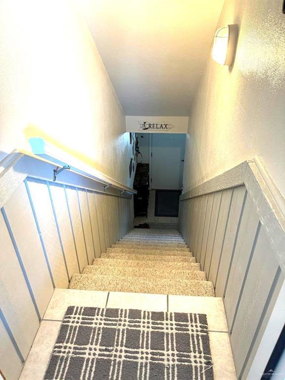 stairway with a textured wall and a wainscoted wall