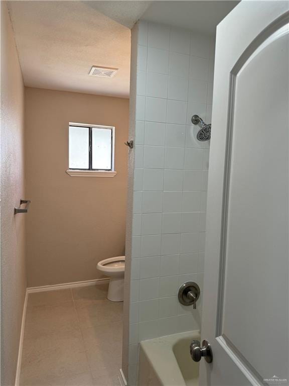 bathroom with toilet, tiled shower / bath combo, and tile patterned floors