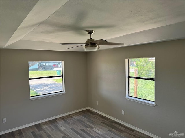 spare room with plenty of natural light, ceiling fan, and dark hardwood / wood-style flooring