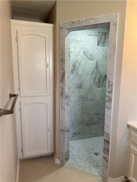 bathroom featuring tile patterned flooring, vanity, and tiled shower