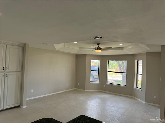 unfurnished room with ceiling fan and a tray ceiling