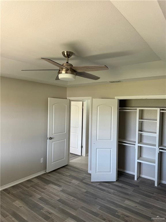 unfurnished bedroom featuring ceiling fan, a closet, and dark wood-type flooring