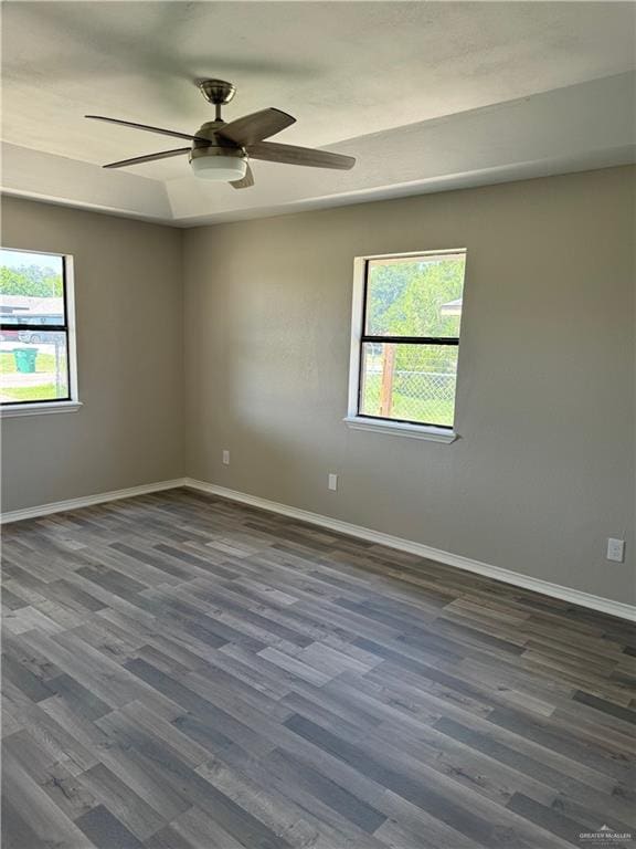 unfurnished room featuring ceiling fan, a healthy amount of sunlight, and dark hardwood / wood-style flooring