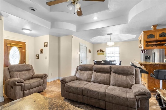 living room featuring a tray ceiling, plenty of natural light, and ceiling fan