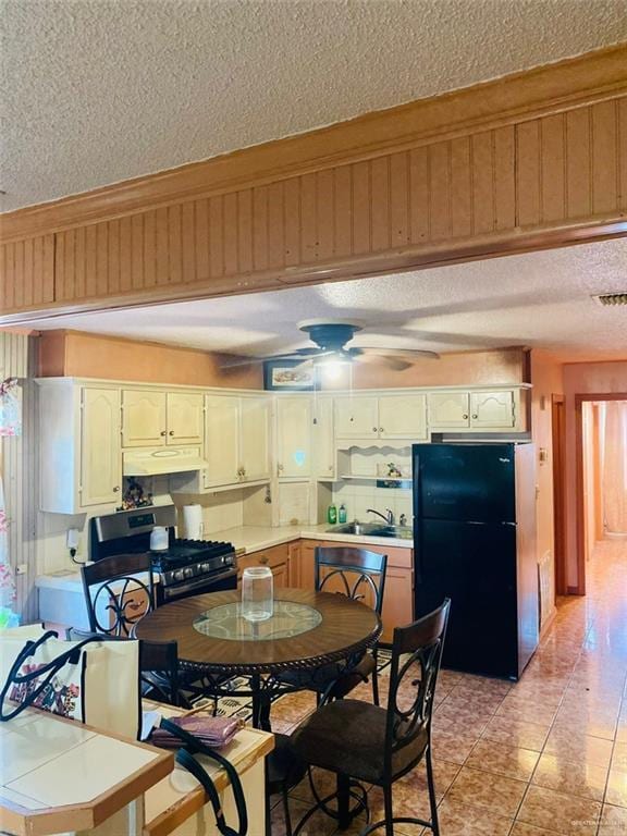 1204 E 2nd St, Weslaco, TX 78596 - kitchen with freestanding refrigerator, stainless steel range with gas cooktop, a textured ceiling, light countertops, and ceiling fan