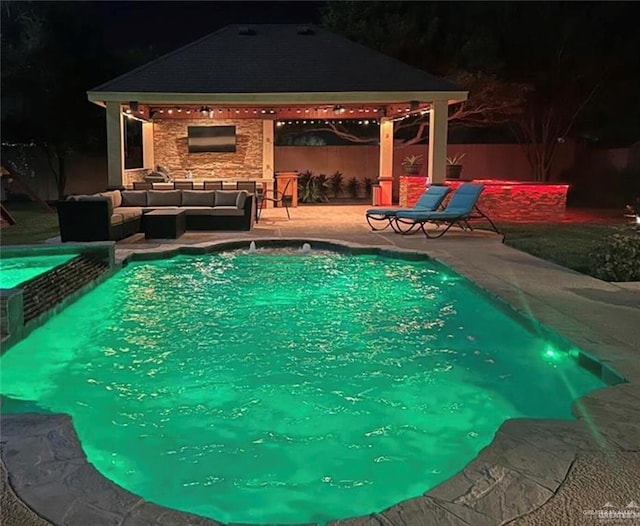 pool at night featuring an outdoor living space with a fireplace, a gazebo, and a patio