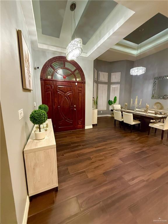 foyer entrance with a tray ceiling, dark hardwood / wood-style floors, and a notable chandelier