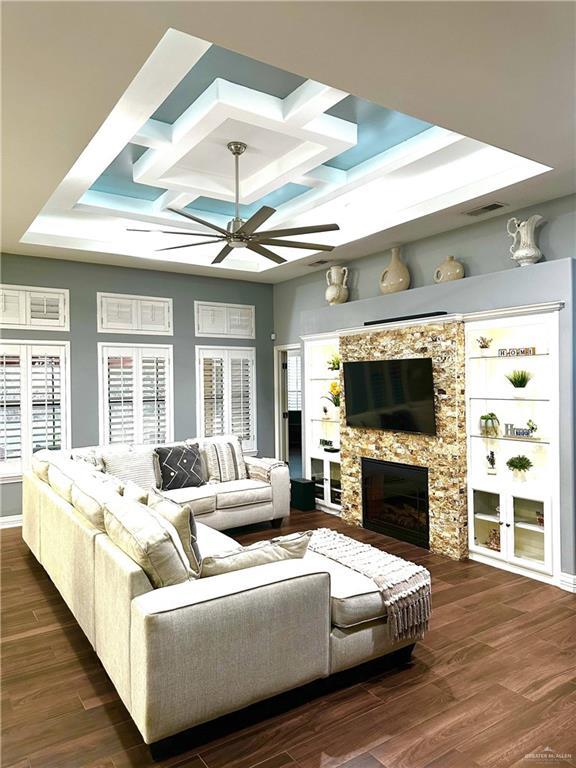 living room featuring a fireplace, dark hardwood / wood-style flooring, a raised ceiling, and a healthy amount of sunlight