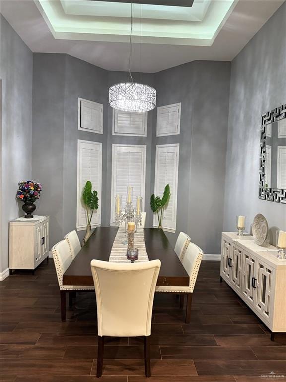 dining space with a tray ceiling, a towering ceiling, and dark hardwood / wood-style floors