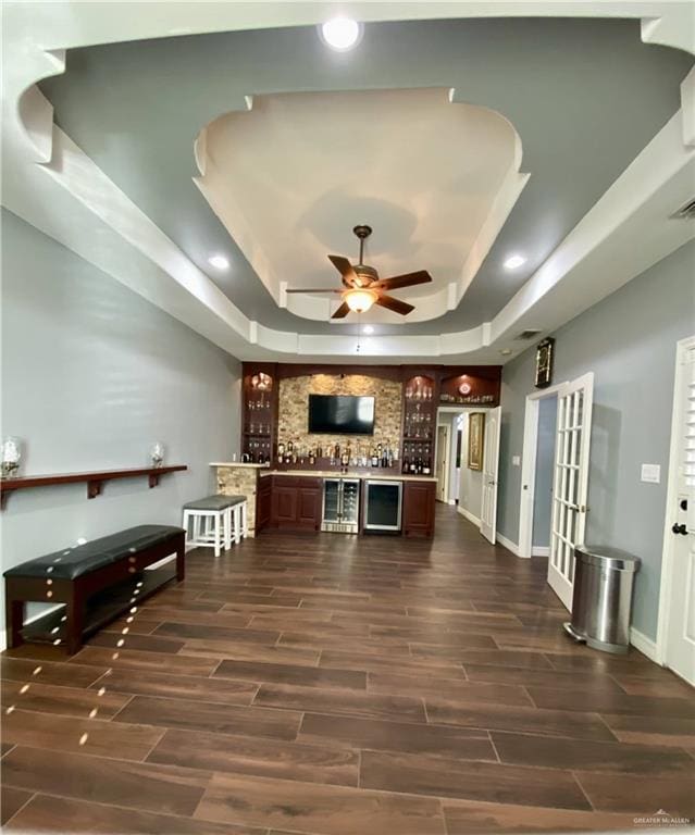 kitchen featuring a raised ceiling, dark brown cabinetry, ceiling fan, and dark hardwood / wood-style flooring