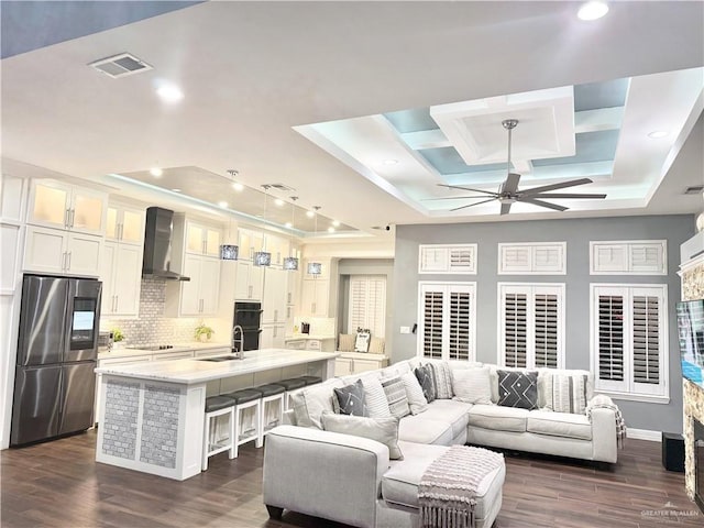 living room featuring ceiling fan, sink, dark wood-type flooring, and a tray ceiling