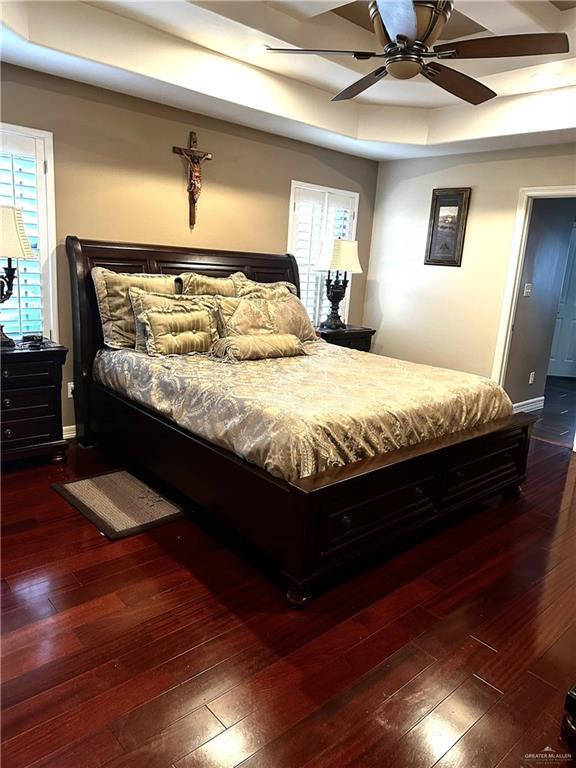 bedroom featuring dark hardwood / wood-style floors, a raised ceiling, and ceiling fan