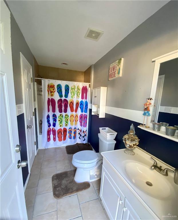 bathroom with toilet, vanity, tile patterned floors, and walk in shower