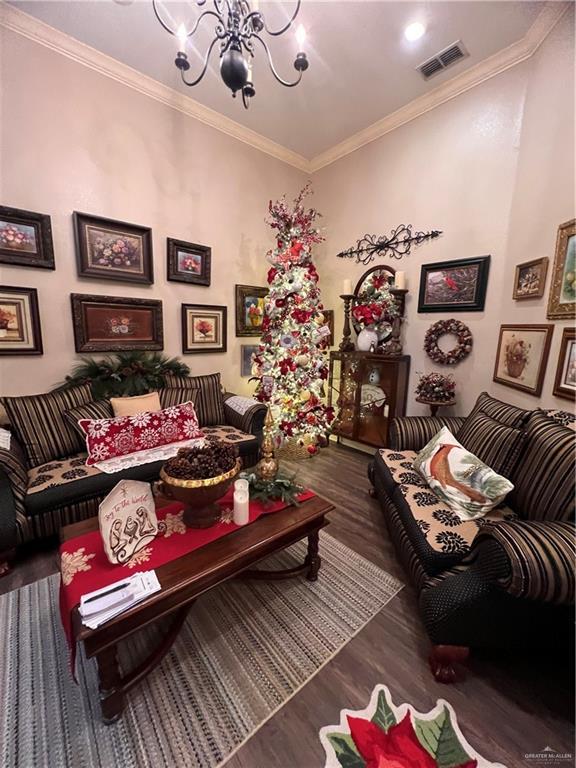 living room featuring dark hardwood / wood-style floors, ornamental molding, and an inviting chandelier