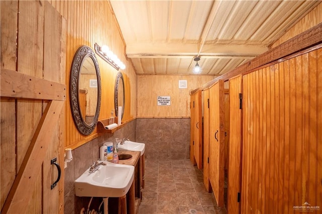 bathroom featuring tile patterned floors, wood walls, sink, and beam ceiling