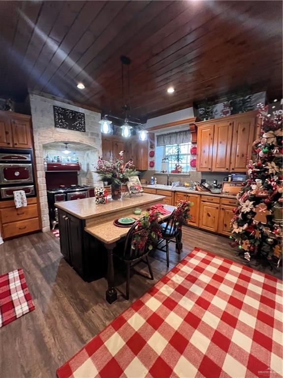 kitchen featuring pendant lighting, dark hardwood / wood-style floors, a kitchen island, and wood ceiling