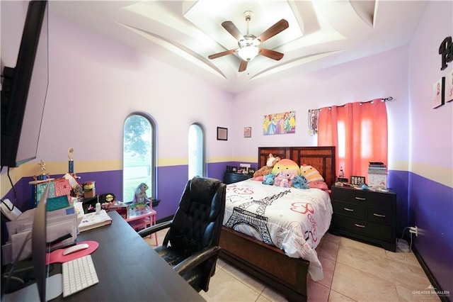 tiled bedroom with ceiling fan and a tray ceiling