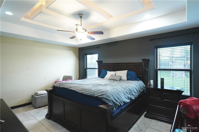 tiled bedroom with ceiling fan and a tray ceiling