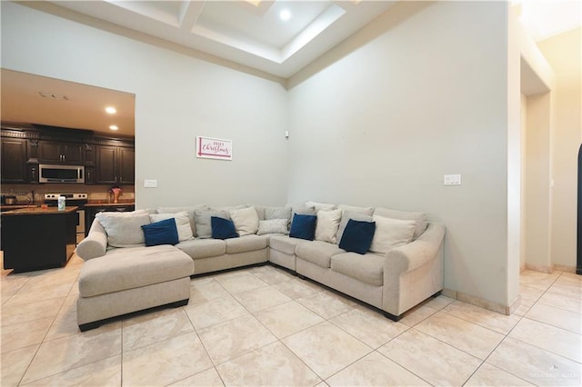 living room with light tile patterned flooring, coffered ceiling, and a high ceiling