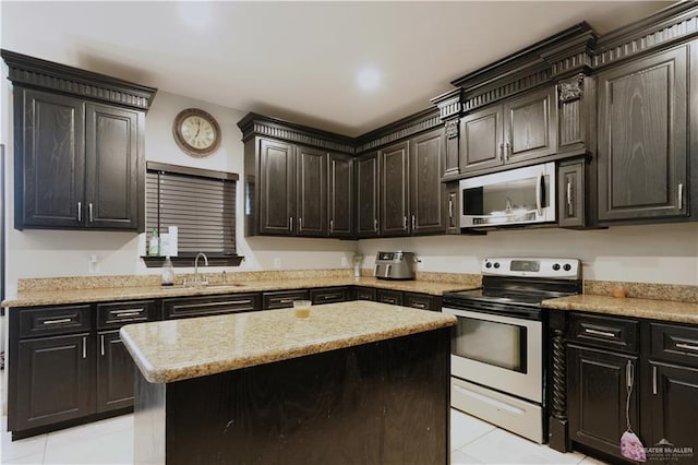 kitchen with sink, light tile patterned floors, light stone counters, a kitchen island, and stainless steel appliances