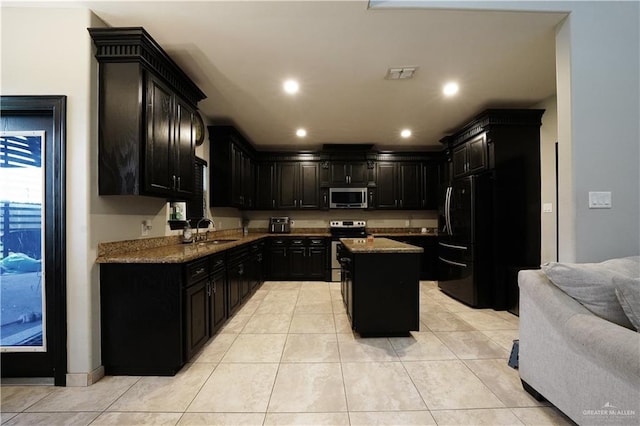 kitchen with sink, a kitchen island, appliances with stainless steel finishes, and light tile patterned flooring