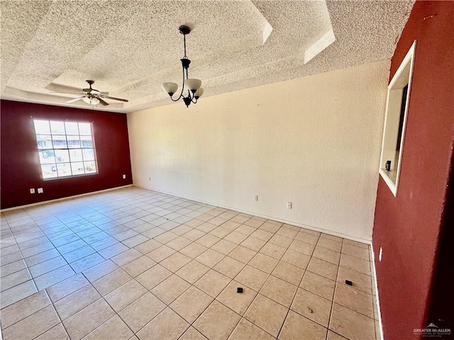 empty room with a raised ceiling, a textured ceiling, light tile patterned flooring, and ceiling fan with notable chandelier