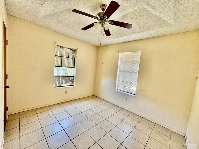 empty room featuring light tile patterned floors, a ceiling fan, and a textured ceiling