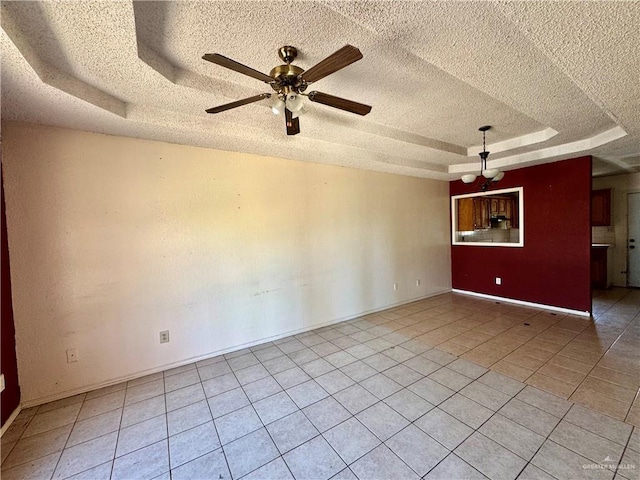 unfurnished room with baseboards, light tile patterned floors, a textured ceiling, a raised ceiling, and a ceiling fan