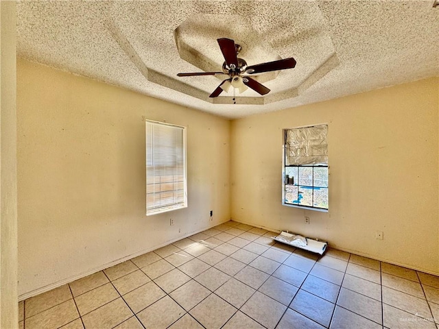 empty room featuring light tile patterned floors, a raised ceiling, a textured ceiling, and a ceiling fan