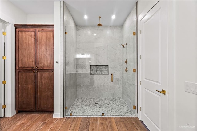 bathroom with hardwood / wood-style flooring and a shower with door