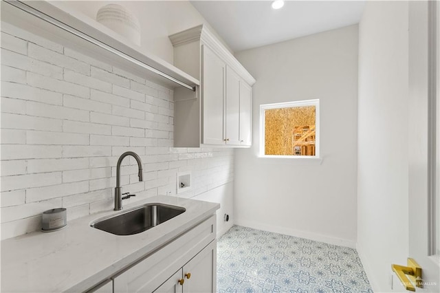 kitchen with white cabinetry, sink, tasteful backsplash, and light stone countertops