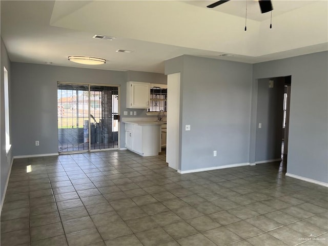 unfurnished living room featuring tile patterned floors, ceiling fan, and sink